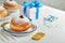 Happy Hanukkah. Hanukkah sweet doughnuts, gift boxes, white candles and chocolate coins on white wooden background. Image and