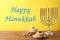 Happy Hanukkah. Silver menorah, dreidels and sufganiyot on wooden table against yellow background