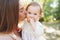 Happy harmonious family outdoors. mother kissing her baby, playing in the summer on the nature