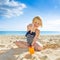 Happy healthy child in swimwear on beach pointing at sun screen