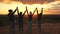 Happy healthy family travels. mom dad and children walk on top of the hill at sunset and joyfully raise their hands and
