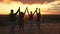 Happy healthy family travels. mom dad and children walk on top of the hill at sunset and joyfully raise their hands and