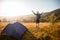 Happy hiker man meet sunset on mountain top. Tourist admire inspirational landscape with hands up.