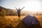 Happy hiker man meet sunset on mountain top. Tourist admire inspirational landscape with hands up