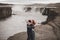 Happy hipster couple kissing in love with view of Iceland Selfoss waterfall