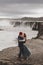 Happy hipster couple kissing in love with view of Iceland Selfoss waterfall