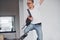 Happy hipster guy in casual clothes and with backpack jumping indoors against white wall