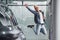 Happy hipster guy jumping indoors against grey background and near car