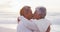 Happy hispanic just married senior couple kissing on beach at sunset