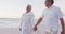 Happy hispanic just married senior couple walking on beach at sunset