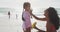 Happy hispanic mother applying sun cream on daughter face on beach