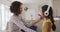 Happy hispanic mother and daughter wearing headphones listening to music sitting on sofa