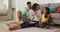 Happy hispanic parents and daughter sitting on floor using laptop