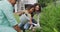 Happy hispanic parents and daughter watering flowers in the garden