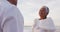 Happy hispanic senior woman taking a vow to man on beach at sunset