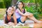 Happy hispanic sisters reading in the park