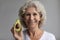 Happy hoary senior mature retired woman showing avocado.