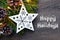 Happy Holidays.Christmas decoration with fir tree, garland lights and white wooden christmas star on old wooden background.