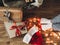 Happy holidays. Christmas gift boxes, festive lights, santa hat and girl legs in cozy socks on wooden floor in christmas eve. Top