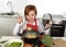 Happy home cook woman in red apron at domestic kitchen holding saucepan with soup tasting delicious vegetable stew