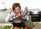 Happy home cook woman in red apron at domestic kitchen holding saucepan with soup tasting delicious vegetable stew