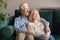 Happy hopeful old couple embracing resting on couch looking away