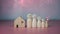 Happy house concept. Model house with wooden dolls standing lined up on pink background and heart icons. Indicates happiness and