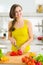 Happy housewife cutting bell pepper in kitchen