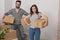 Happy husband and wife carrying boxes in their new house.