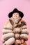 Happy imaginative little boy posing in oversize luxurious fur coat and black hat