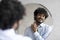 Happy indian businessman in shirt and necktie spraying perfume on his neck while looking and smiling in the mirror