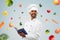 Happy indian chef with cookbook over vegetables