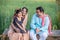 Happy Indian farmer family sitting on traditional bed at agricultural field in village, Young couple with their daughter in