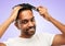 Happy indian man brushing hair with comb