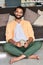 Happy indian man looking at camera drinking coffee at home. Vertical portrait