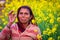 Happy Indian old woman standing in mustard field.