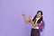 Happy indian school girl pointing advertising isolated on violet background.
