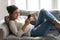 Happy Indian woman relaxing on couch at home, using phone