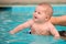 Happy infant baby boy enjoying his first swim