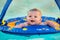 Happy infant playing in pool while sitting in baby float