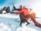 Happy influencers couple having fun with wood vintage sledding on snow high mountains - Young crazy people enoying winter vacation