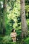 Happy innocent woman sitting in green atmospheric forest on background of mountains in summer