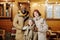 Happy intercultural family of three in winterwear standing by cottage