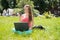 Happy internet shopping woman online with laptop and credit card sitting outdoor on green grass. Internet shopper buying things on