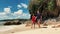 Happy interracial couple walking on the white sand beach shore at summer day.