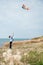 Happy ittle boy holding flying kite on sea background