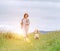 Happy jogging smiling female with fluttering hairs and her beagle dog running and looking at eyes. Walking by meadow grass path in