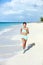 Happy jogging woman running on sunny beach living a fit life