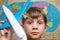 A happy and joyful boy is holding an airplane against the background of the atlas of the world, tourism and travel