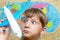 A happy and joyful boy is holding an airplane against the background of the atlas of the world, tourism and travel